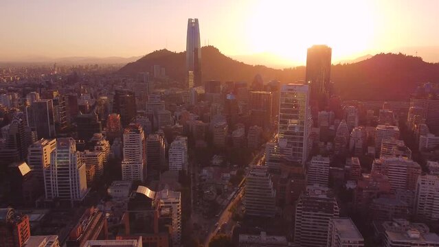 Santiago de Chile shows movement in its streets, cars pass between its large and modern buildings at sunset.