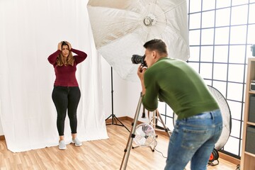 Young woman at photography studio suffering from headache desperate and stressed because pain and migraine. hands on head.