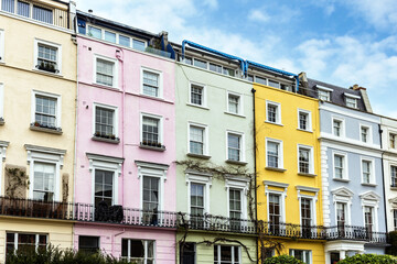 Fototapeta na wymiar Colourful terraced townhouses with summer sky background. The area of Notting Hill, London, is famous for streets of houses with brightly painted exteriors.