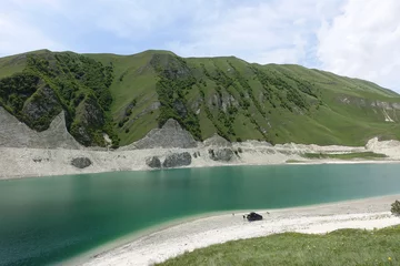 Fotobehang A car on the background of Lake Kezenoy-am in the Caucasus mountains in Chechnya, Russia, June 2021. © Виктория Балобанова
