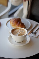 Cup of coffee and croissant, latte art.