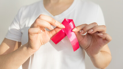 prevention of breast cancer. manual examination of the breast.woman doing manual breast examination. pink ribbon as a symbol of World Breast Cancer Day. symbol of public consciousness,selective focus