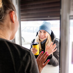 buying coffee to go. young woman holding a cup of coffee and waving to barista. selective focus,