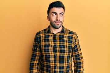 Young hispanic man wearing casual clothes smiling looking to the side and staring away thinking.