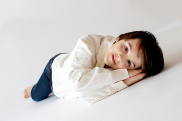 Cute stylish toddler child and older brothers, boys with white shirts on white background, family kids portrait