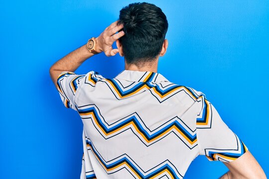 Young hispanic man wearing casual clothes backwards thinking about doubt with hand on head