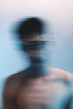 Blurry portrait of topless man against light background