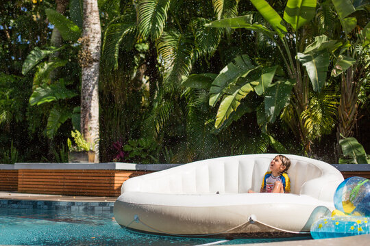Boy sitting on inflatable couch in swimming pool