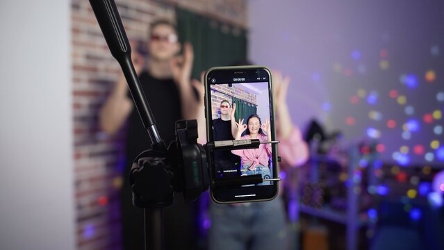 A guy and a girl dance on a smartphone camera. A view of the phone screen standing on a tripod. Social network. Blogger