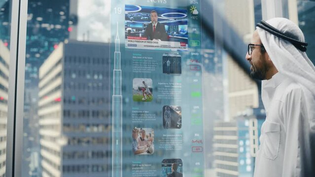 Successful Muslim Businessman in Traditional White Clothes Checking News Messages on Futuristic Augmented Reality Screen in Glass Elevator in Business Center. Saudi, Emirati, Arab Businessman Concept.