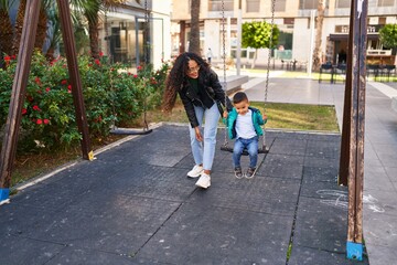 Mother and son playing on swing at park