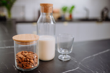 Almond milk and glass on kitchen counter. Healthy vegan product concept.