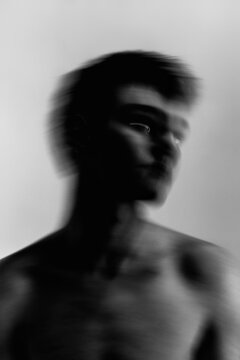 Grayscale blurry portrait of topless man against light background