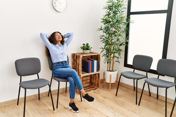 Young latin woman relaxed with hands on head listening to music at waiting room