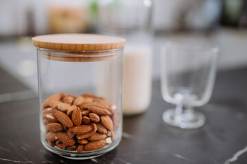 Almonds and almond milk and glass on kitchen counter. Healthy vegan product concept.