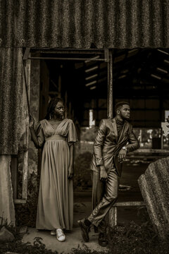 Grayscale photo of woman in dress standing beside a man in a suit