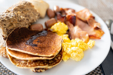 Close-up plate with English breakfast. Pancakes, eggs, sausages and bread.