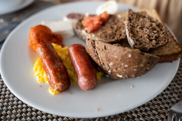 Close-up abundant continental breakfast with rye bread, eggs and sausages