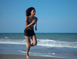 African American girl in sportswear running on beach