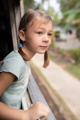 girl with pigtails looks out the train window