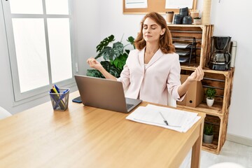 ¡Young caucasian businesswoman meditating doing yoga exercise at the office.