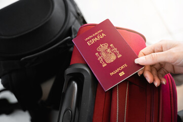 Unrecognizable female hand holds a Spanish European passport on luggage.