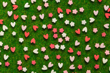 Confetti in the shape of hearts and floral red and pink on the background of an artificial lawn. Macro idea for Valentine's Day - 495442688