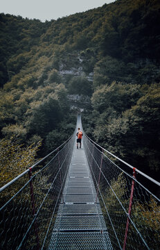Man with backpack walking on hanging bridge