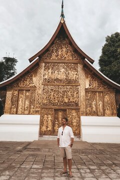 Mature man standing beside Wat Xiengthong temple in  Luang Phrabang, Laos
