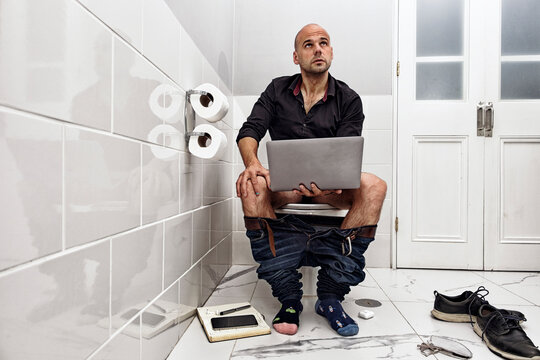 Mature man working online while using the bathroom