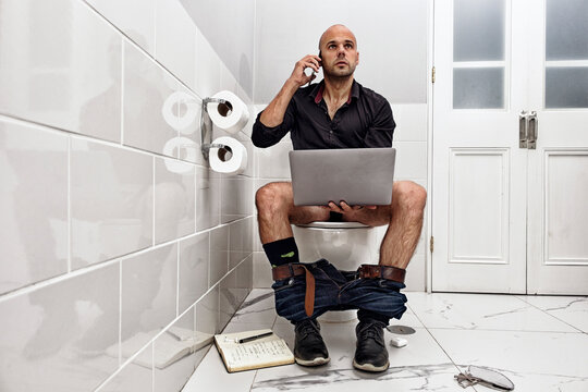 Mature man working online while using the bathroom