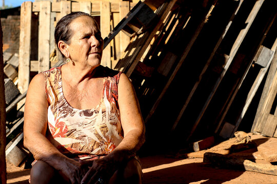 Portrait of an older woman sitting beside wooden wall outdoor