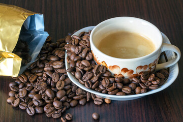 A cup of coffee with coffee beans sprinkled from a bag