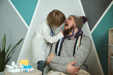 Father and child playing clinic and doctor, little boy dentist in medical gown with stethoscope...