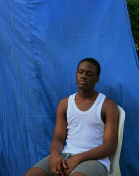 Portrait of man sitting on white chair beside blue wall