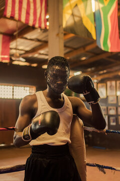 Portrait of Ghanaian boxer wearing flag leaning on corner of boxing ring