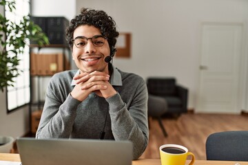 Young hispanic call center agent man smiling happy working at the office.