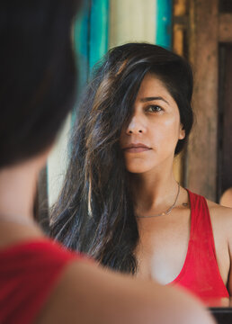 Portrait of South Asian woman in red top reflected on mirror