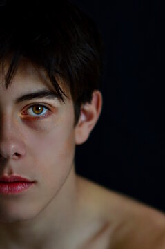 Portrait of topless young man against dark background