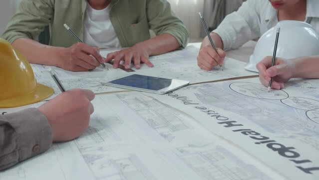 Close Up Of Group Of Asian Engineers Drawing Building Construction At The Office
