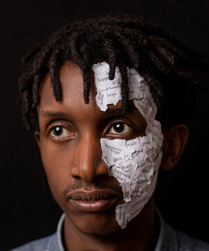 Portrait of young African man with pieces of paper with positive word patched on his face