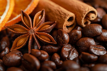 Macro shot of anise, cinnamon and dried orange on coffee beans background.