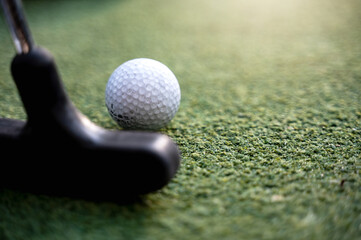 Close-up golf club and ball on grass.
