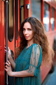 Side view of mature woman in blue dress standing beside red train