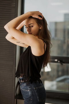 Side view of woman in dark top and jeans posing indoor
