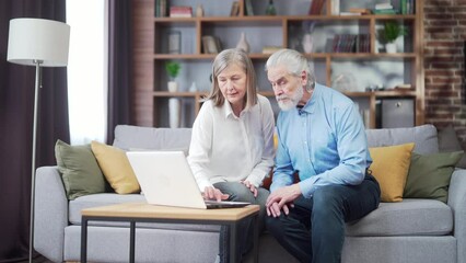 senior couple man and woman shopping online browsing laptop in home. Elderly family Happy retired couple using computerooking at screen and paying on internet. older husband and wife choose the web
