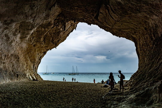 Silhouette of people in a cave at Cala Luna beach in Italy