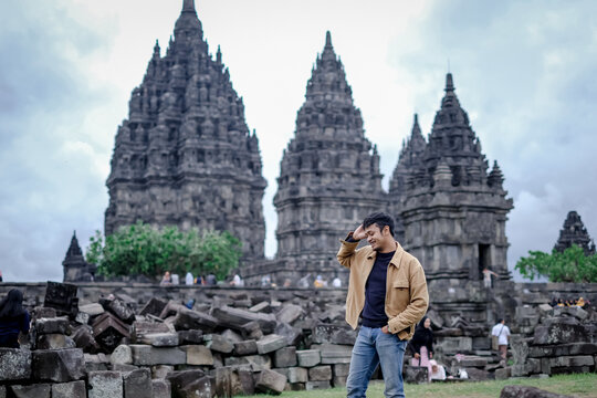 Southeast Asian man in brown jacket walking near Prambanan Temple in Yogyakarta, Indonesia