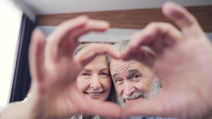 Affectionate happy old senior couple grandparents make heart shape hand gesture. Look at camera bonding laughing showing family love concept,. retired elderly family closeup portrait symbol of love - Powered by Adobe