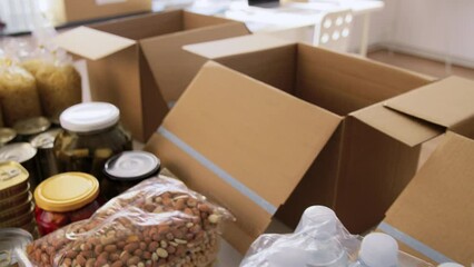 charity, humanitarian aid and donation concept - close up of packed food, drinks and boxes at distribution or refugee assistance center
